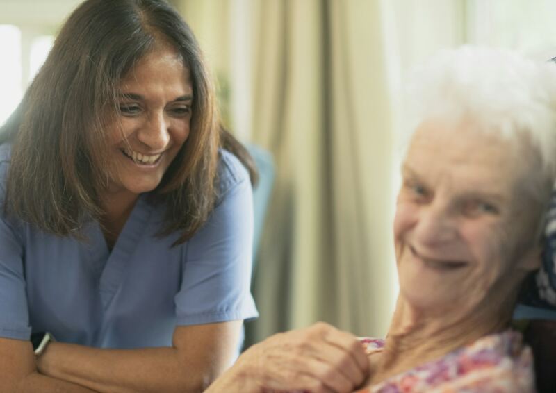A caregiver sharing a laugh with an older woman