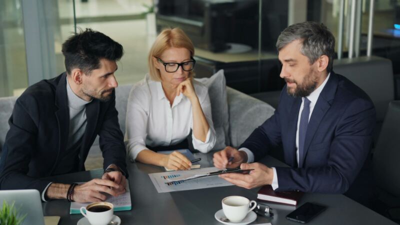 Three colleagues reviewing documents together in a meeting