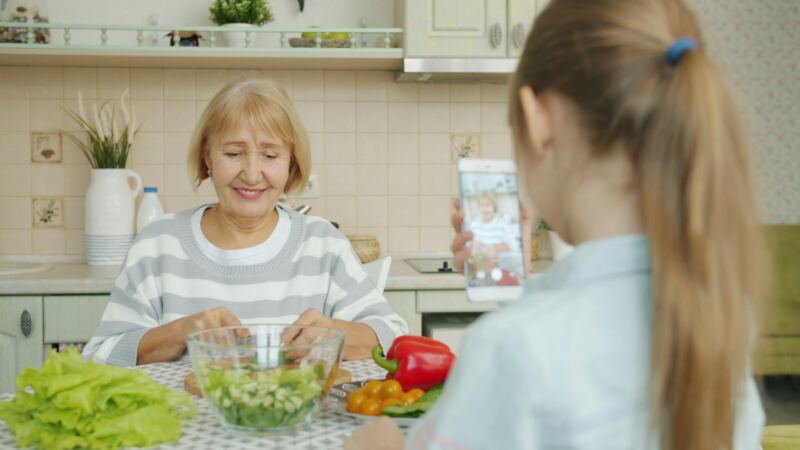 A grandmother and granddaughter making a salad together