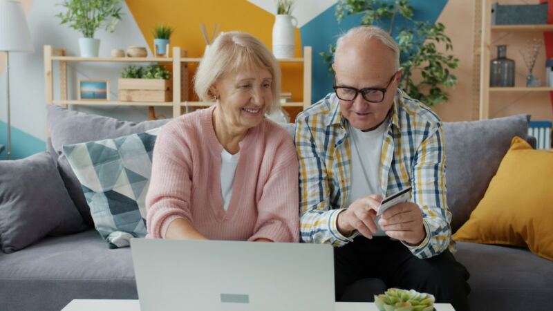 An older couple on their couch, getting their accounts in order on a laptop