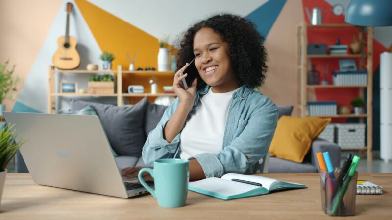 A woman smiling as she talks on the phone at her desk at home