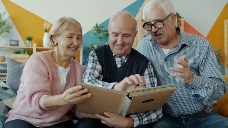 Three older friends looking through a photo album together