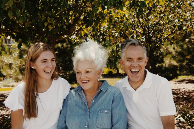 A mother with her adult son and daughter, smiling outdoors